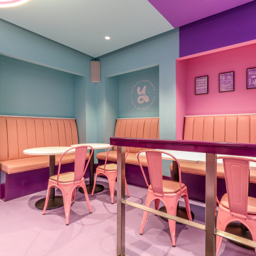 Vibrant seating area in a colorful dessert café designed by Phoenix Wharf, featuring pink and blue decor.