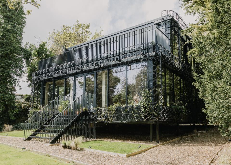 Modern residential architecture featuring handcrafted sculptural surfaces, surrounded by lush greenery in a natural setting.