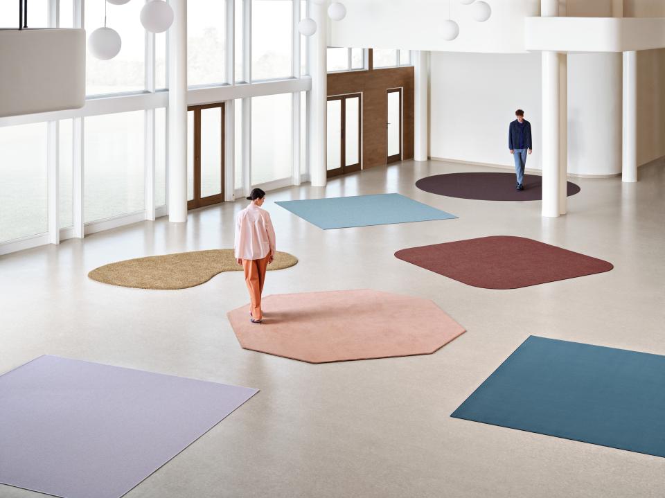 Modern workspace with unique rugs in various shapes, showcasing sustainable design concepts at Orgatec 2024.