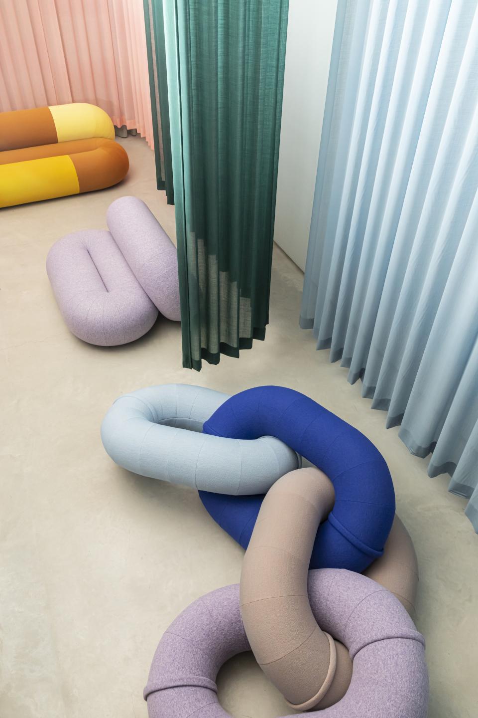 Colorful, sculptural textile forms in a minimalistic space, showcasing innovative design trends from the 2023 design event.