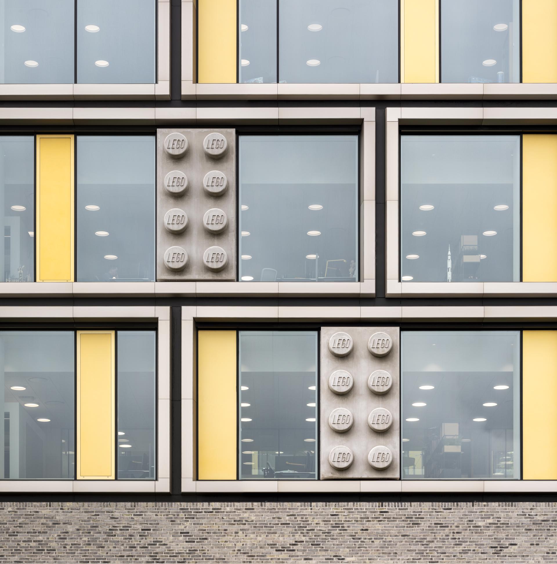 LEGO-inspired architectural design featuring large building blocks and bright yellow accents on a modern office facade.