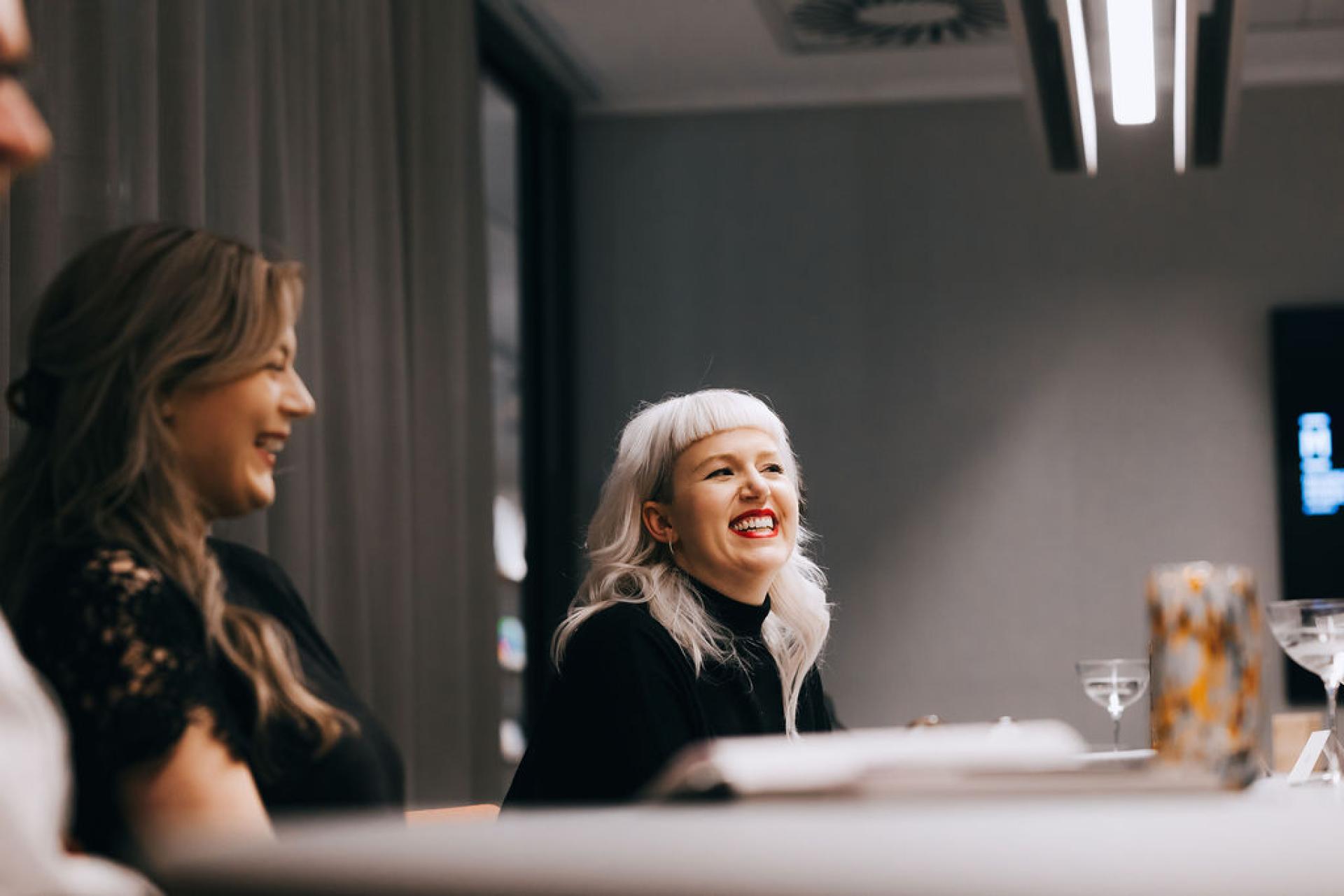 Two women engage in a lively discussion, conveying a sense of joy and collaboration on sustainability topics related to biomaterials.