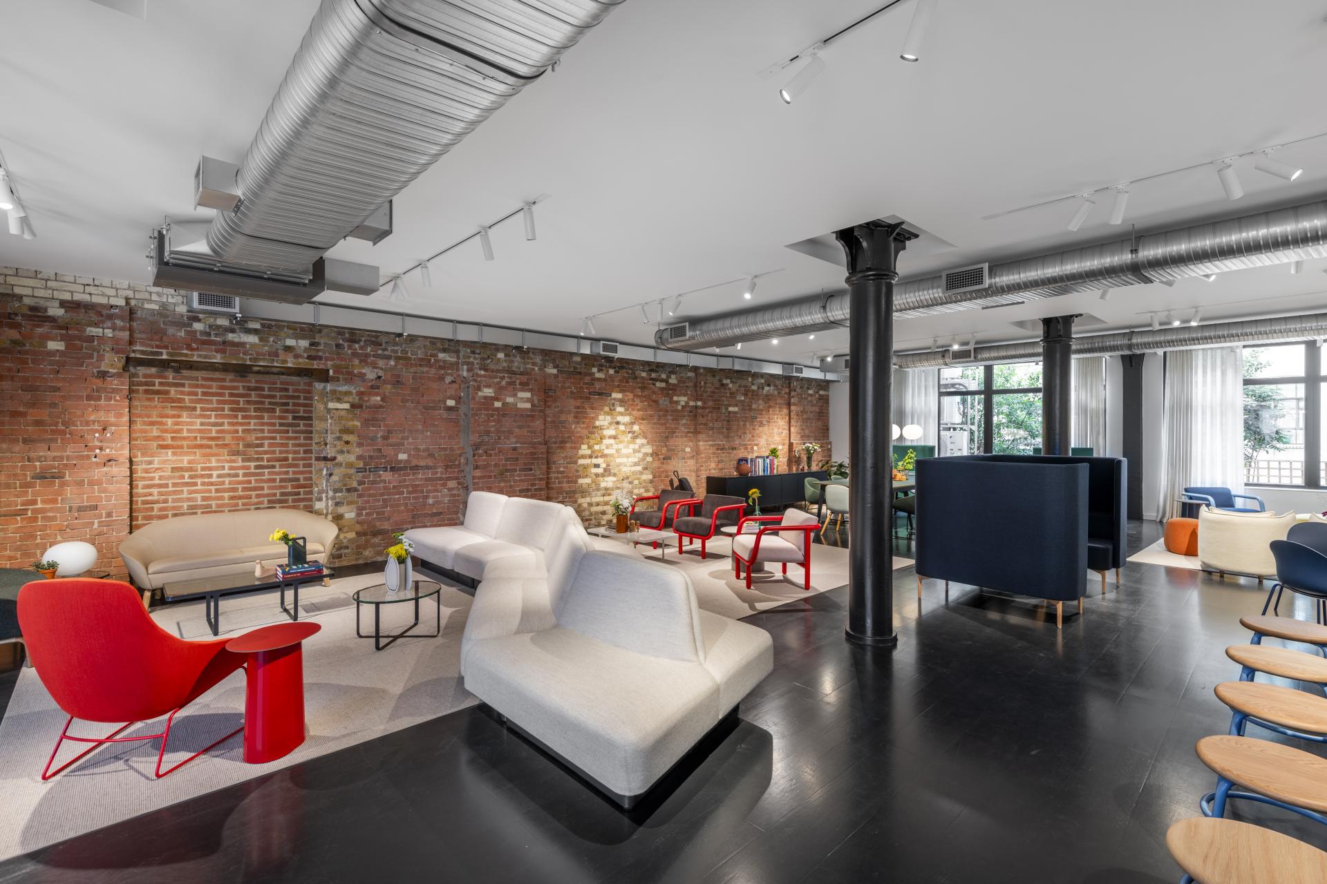 Modern seating arrangements in NaughtOne's flagship showroom showcase vibrant furniture designs against exposed brick walls.