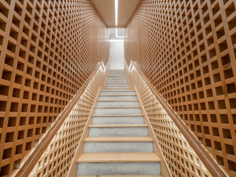 Modern staircase featuring a wooden lattice wall design, embodying the Japandi aesthetic in Brew92's new coffee shop interior.