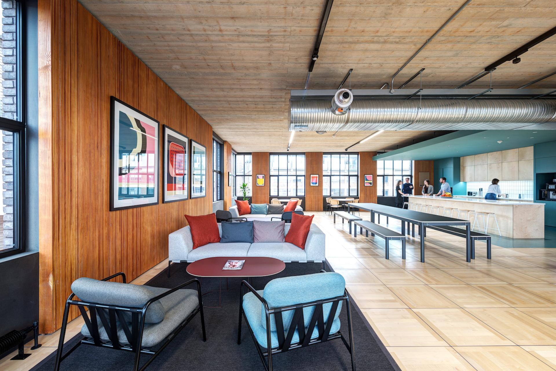 Spacious, modern workspace featuring creative decor, collaborative seating, and a kitchen area, emphasizing post-Covid design and sustainability.