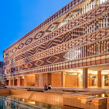 Stunning exterior view of Krushi Bhawan, showcasing its unique brick patterns and reflections in the adjacent water feature.