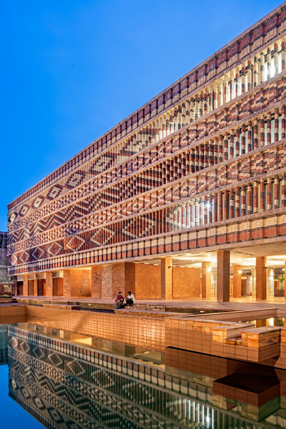 Stunning exterior view of Krushi Bhawan, showcasing its unique brick patterns and reflections in the adjacent water feature.