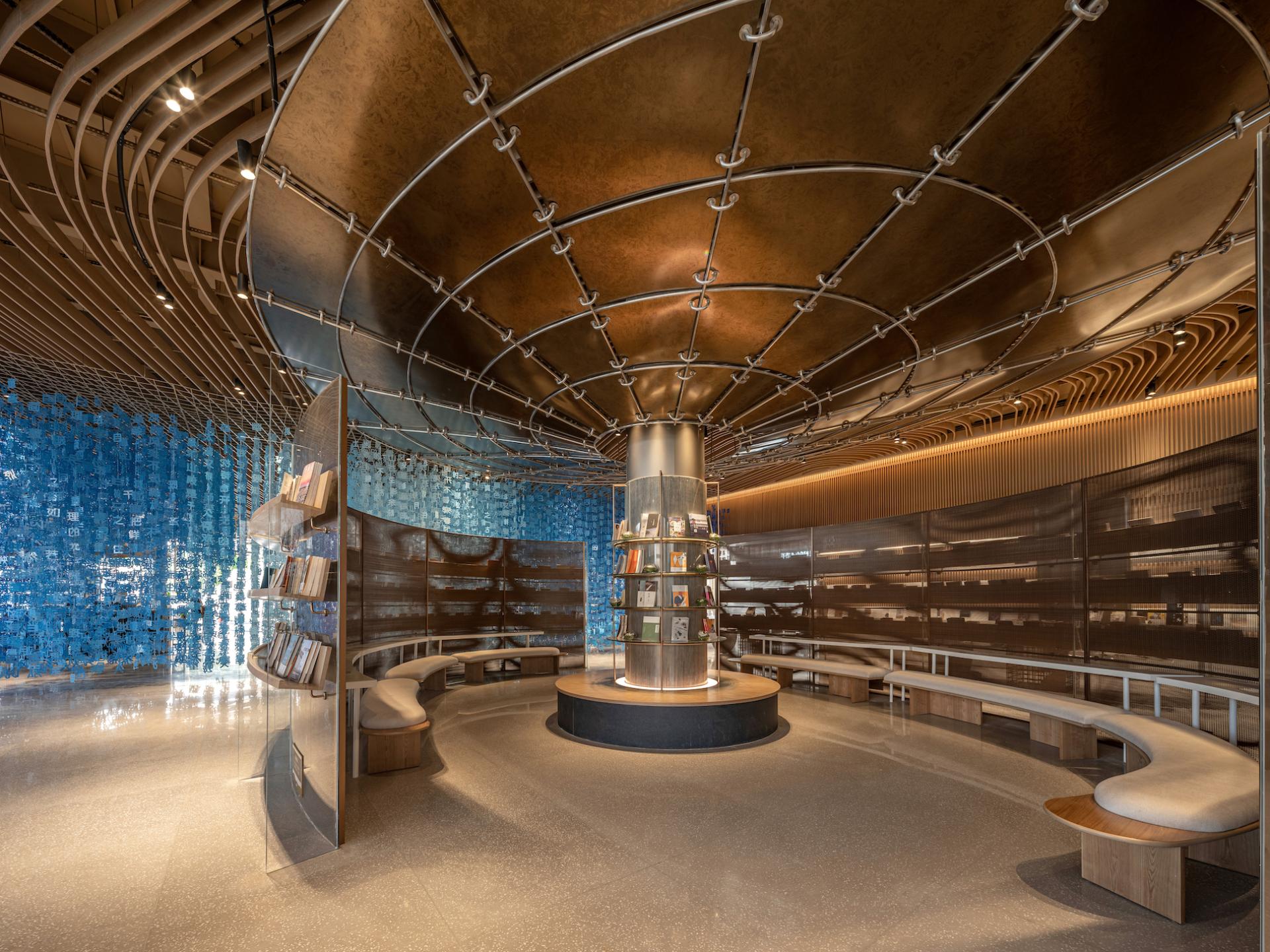 Modern exhibition hall interior featuring sculptural elements, blue glass wall, and inviting reading spaces in Dali, China.
