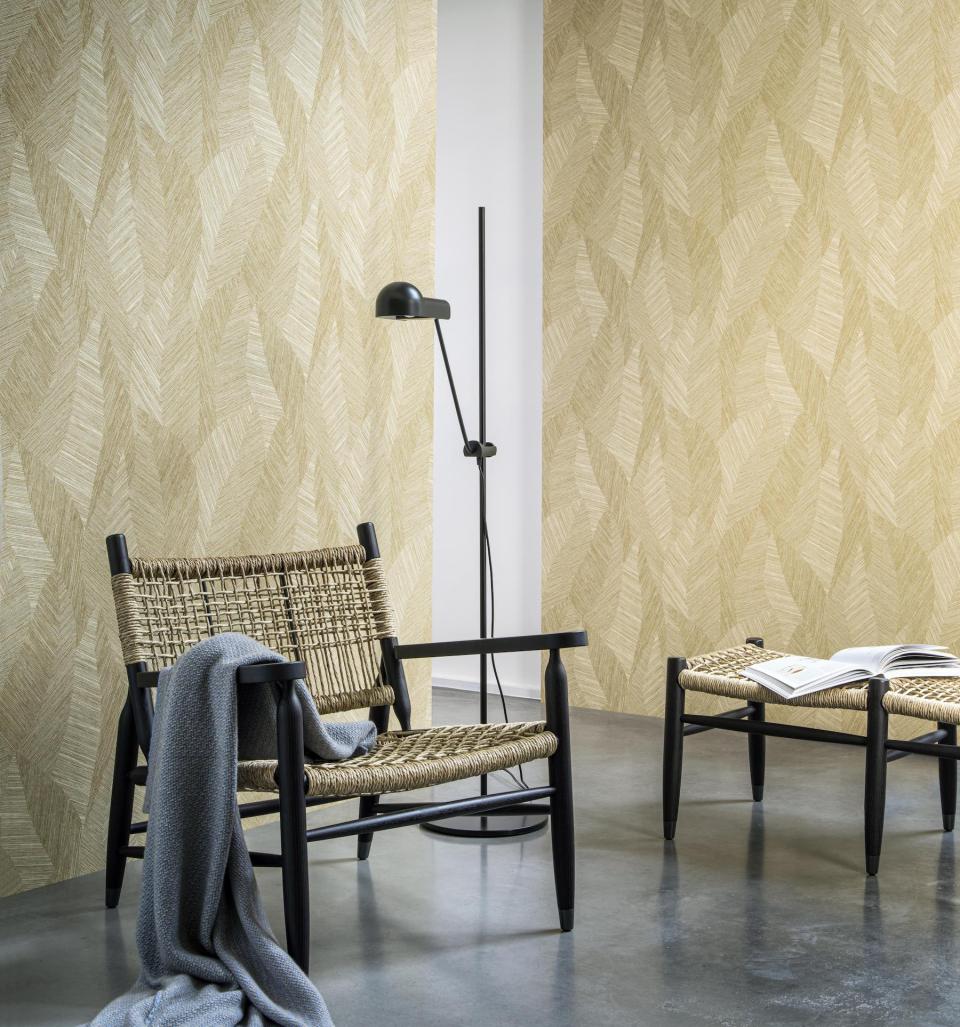 Stylish living room scene featuring woven chairs, a modern lamp, and a textured leaf-patterned wallpaper from the Tangram collection.