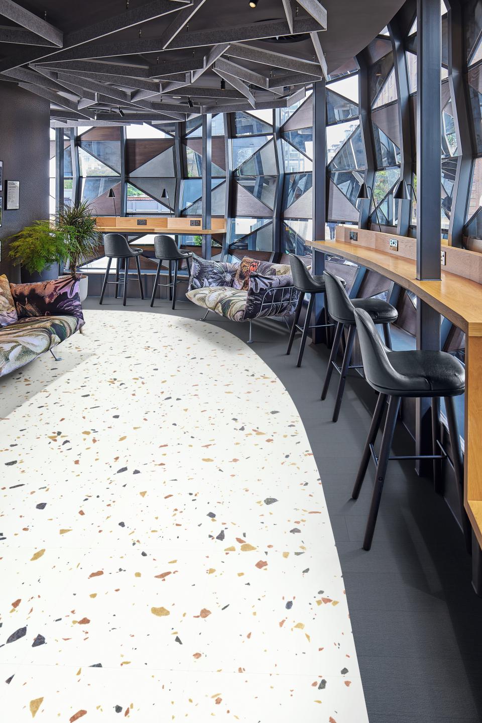 Contemporary workspace featuring Karndean's Opus abstract flooring, with stylish seating and striking geometric windows.