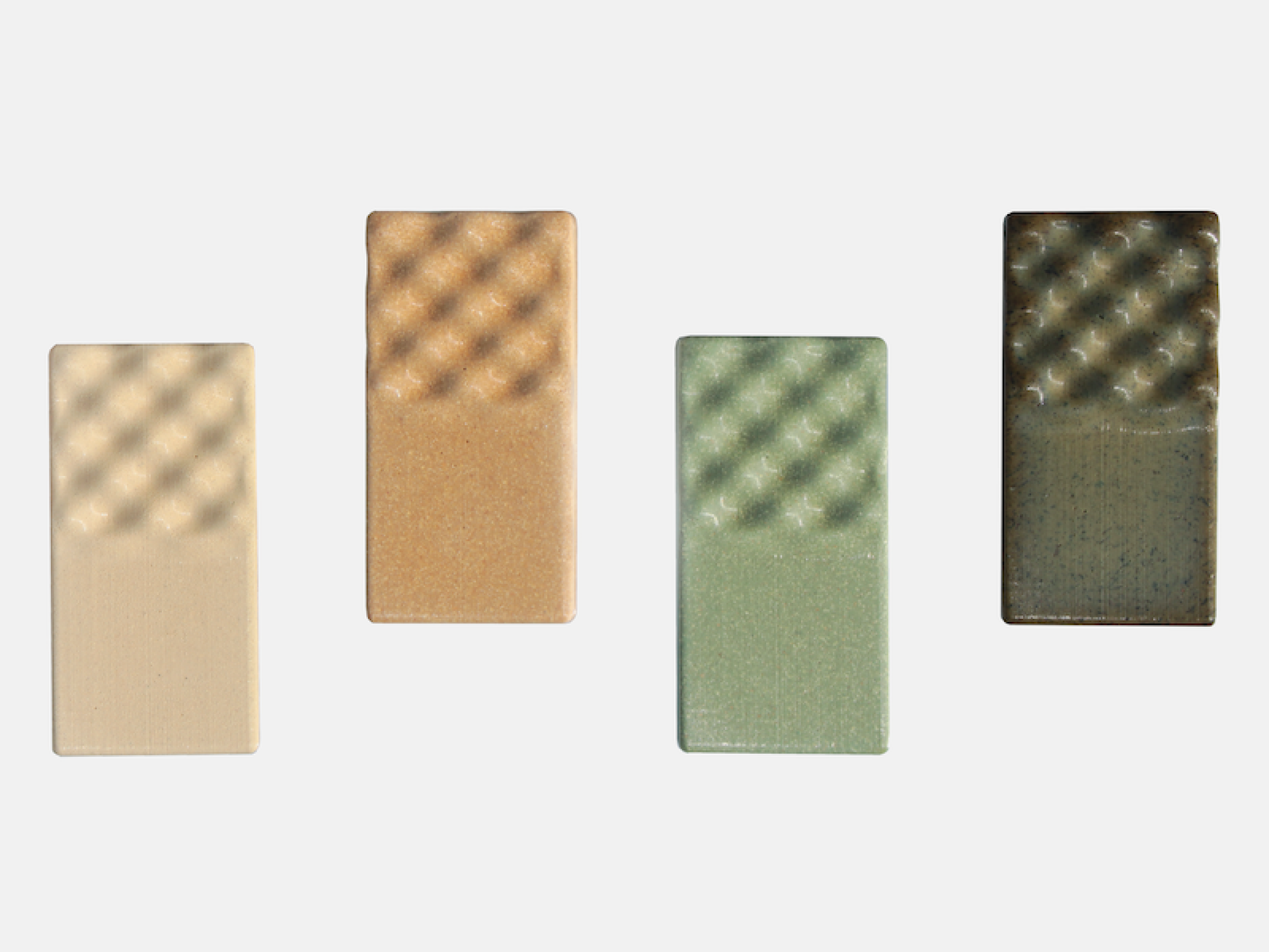 Colorful ceramic tiles with textured surfaces displayed in a row, showcasing designs from Atelier Barb's Bio Series collection.