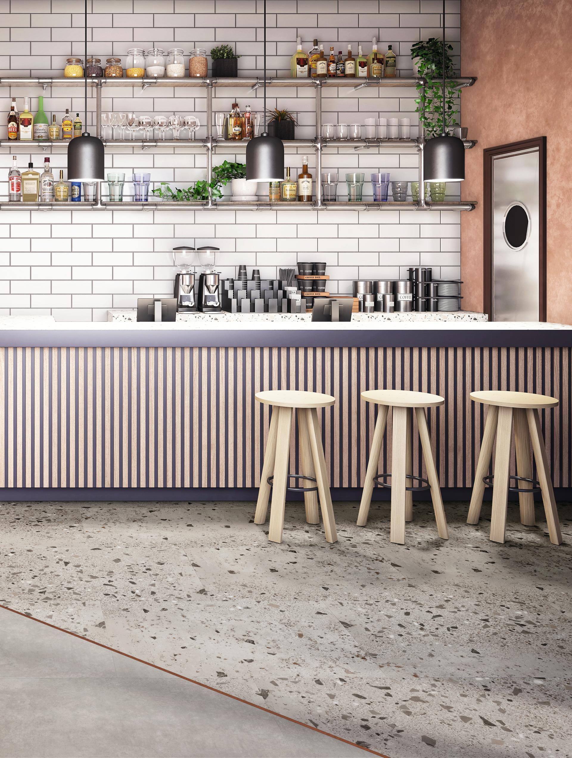 Modern bar interior featuring terrazzo flooring, wooden stools, and a stylish shelf with various beverages.