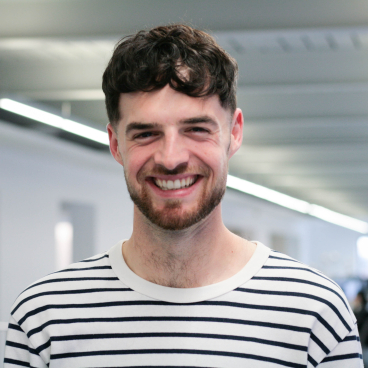 Liam Briggs from Buttress smiling in a modern office, discussing innovative project strategies and interview techniques.
