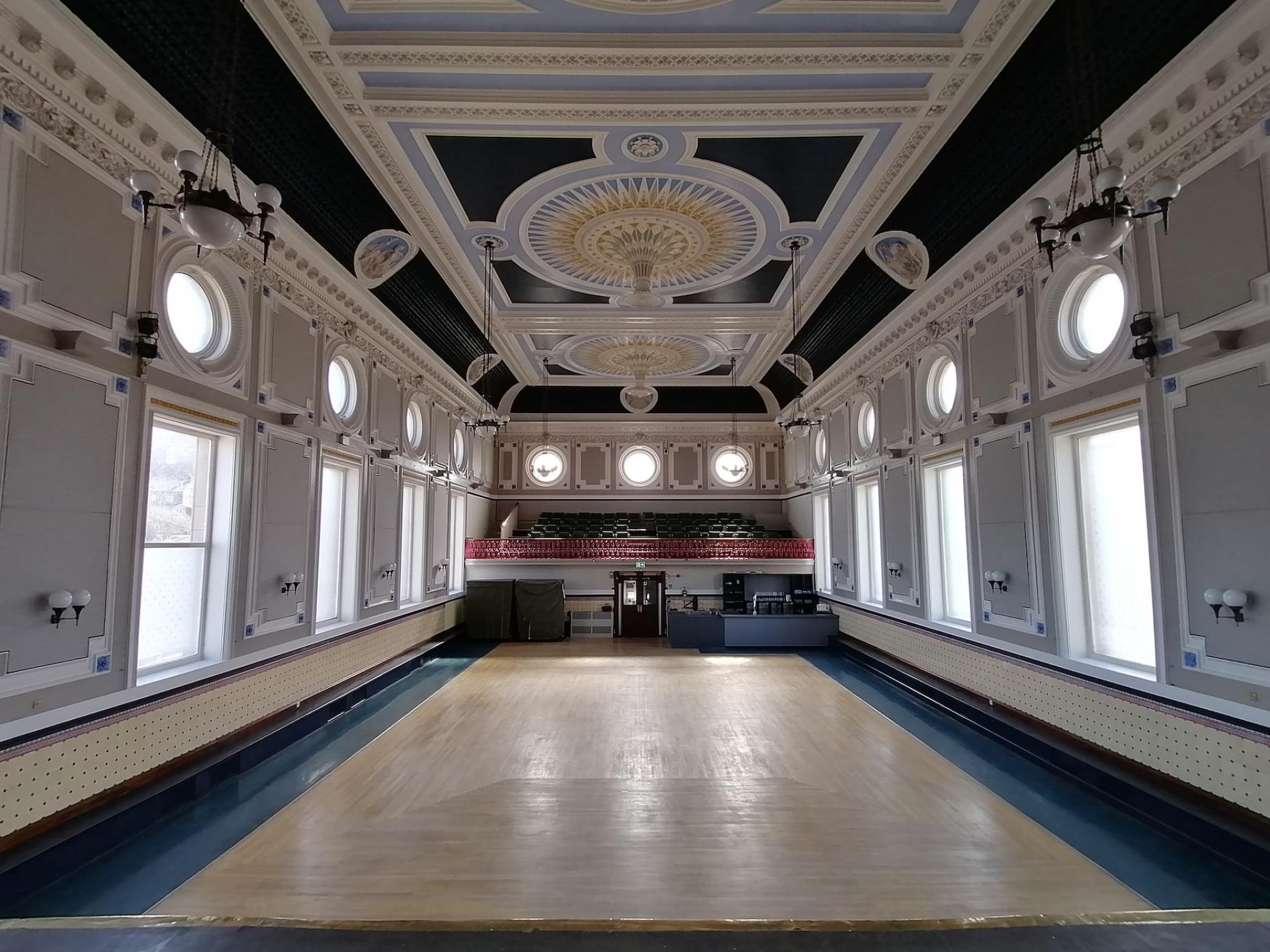 Refurbished ballroom in Todmorden Town Hall, showcasing elegant architectural details and newly polished wooden flooring.