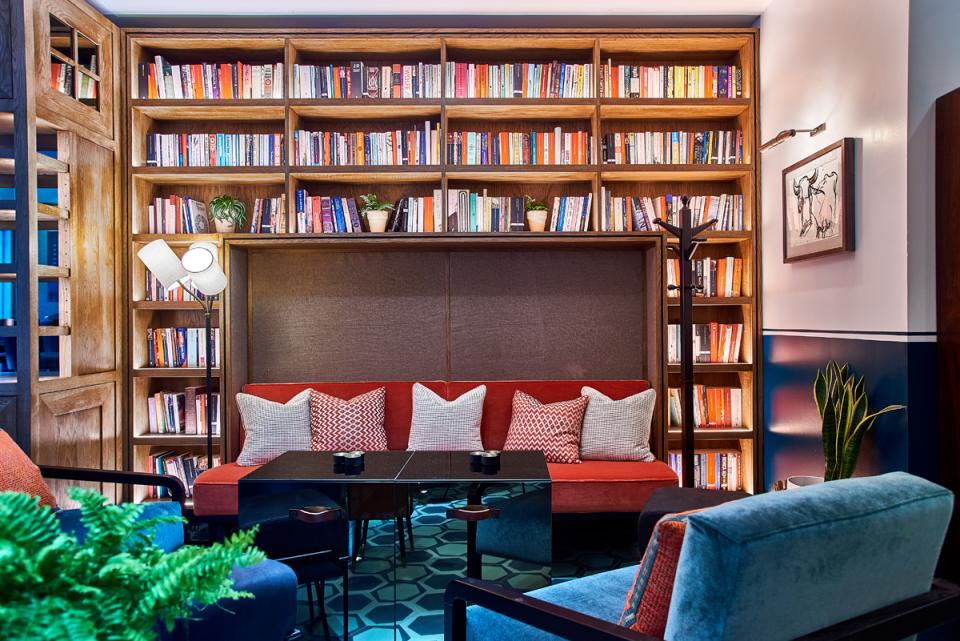 Stylish art deco seating area with a bookshelf, cozy cushions, and a modern lamp in Teatulia's tea shop.
