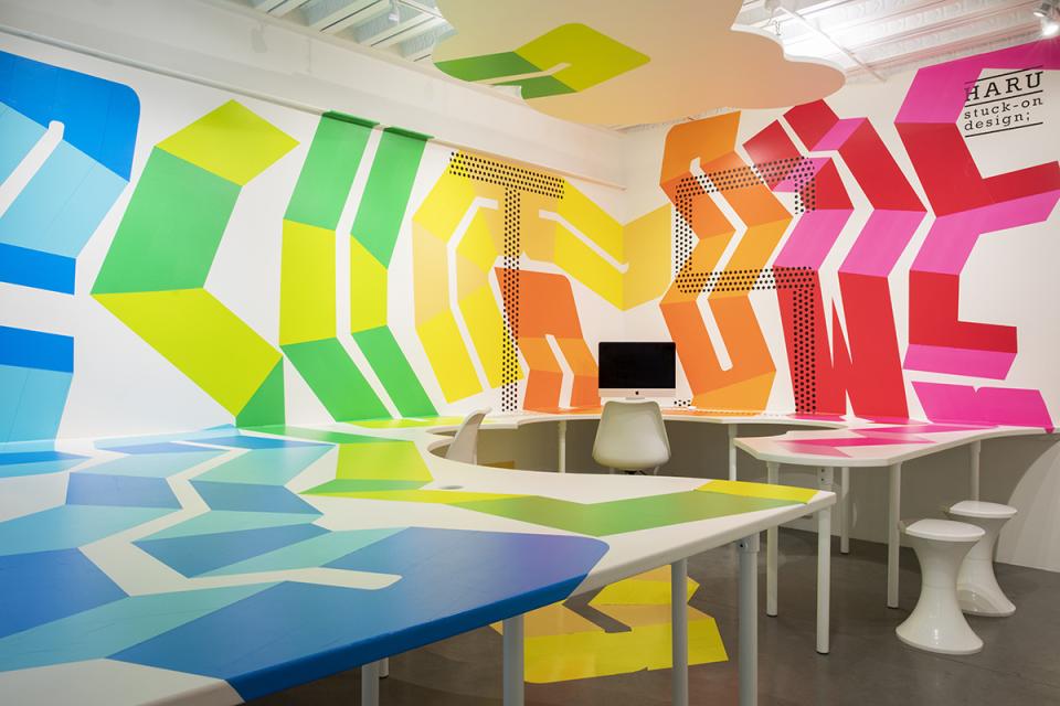 Vibrant interior featuring HARU Stuck-on Design materials, showcasing colorful geometric patterns on walls and workspace surfaces.
