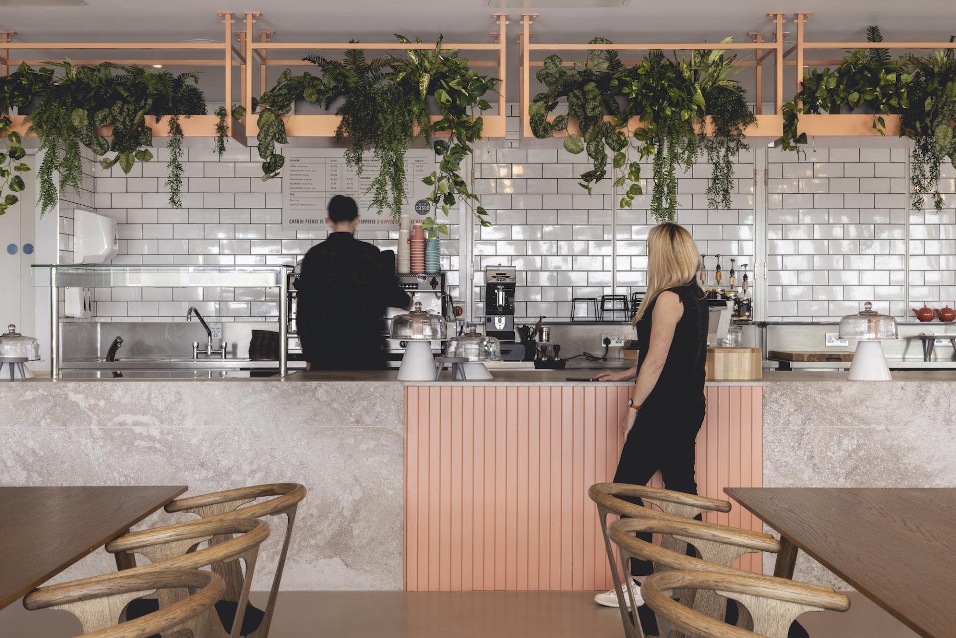Stylish café area in AstraZeneca UK's new workplace design featuring modern decor, greenery, and a barista station.