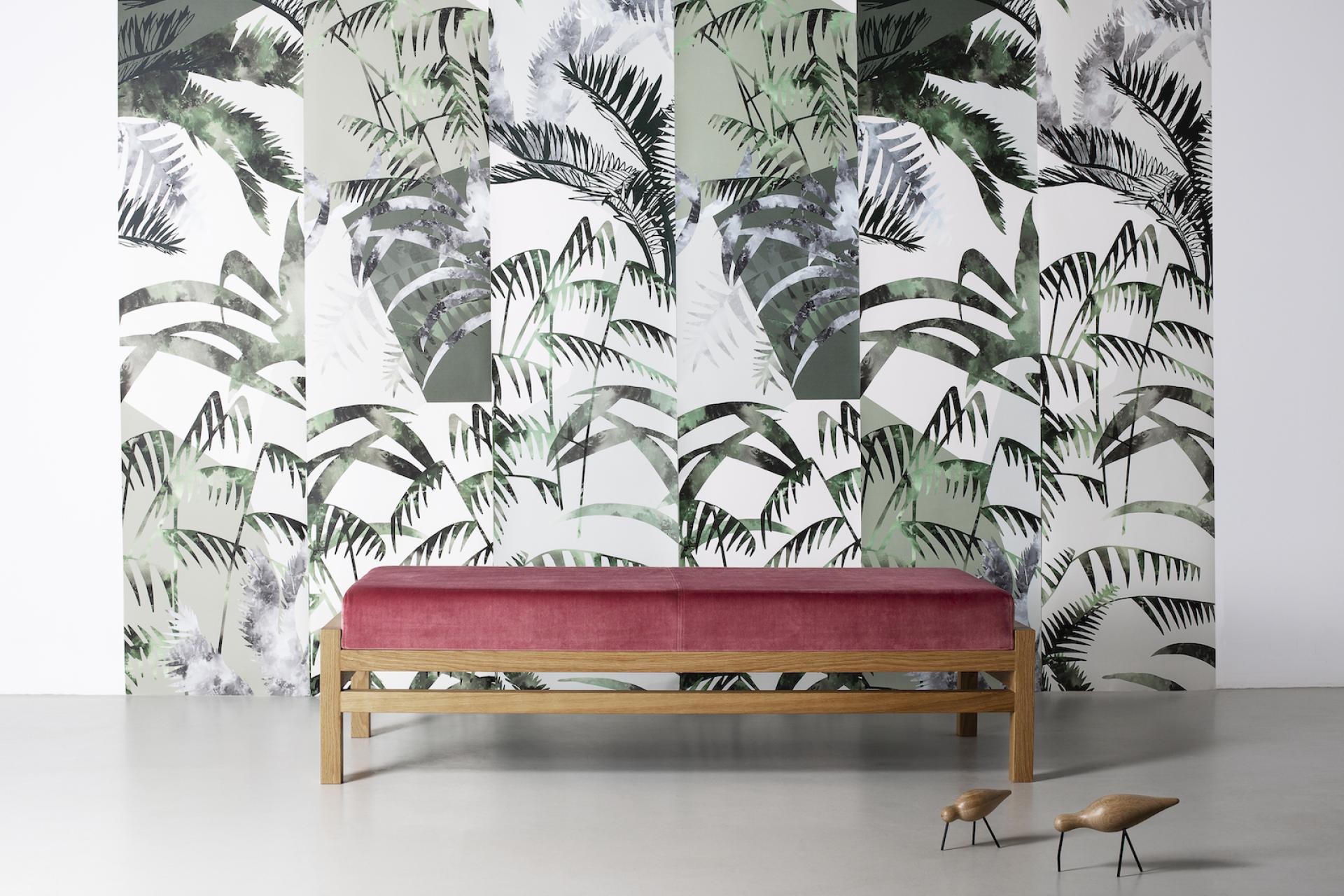 Lush palm-patterned wallpaper creates a vibrant backdrop for a modern bench in a stylish interior setting.