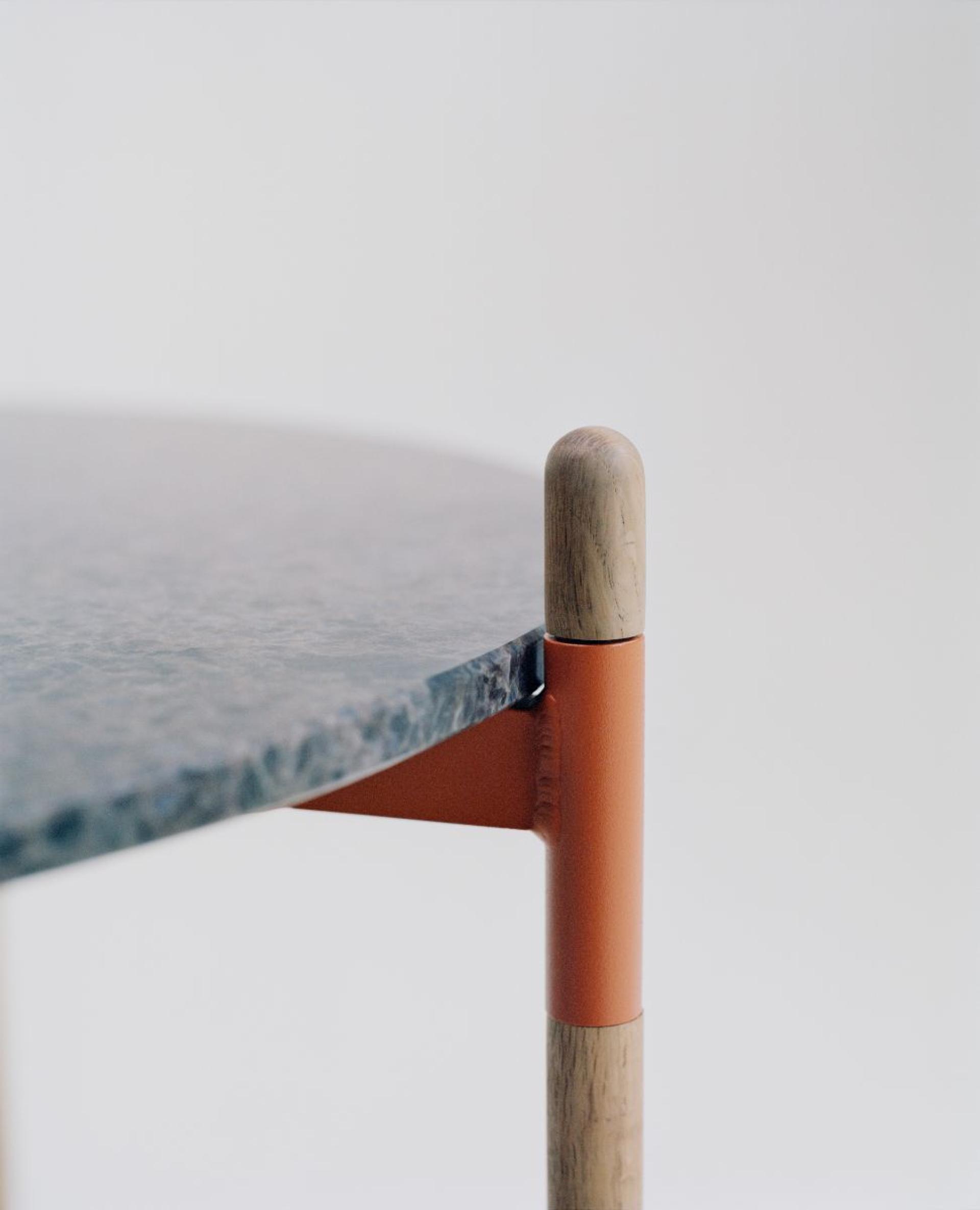 Close-up of a stylish, circular table featuring a marble top and wooden legs, highlighting innovative circular design elements.