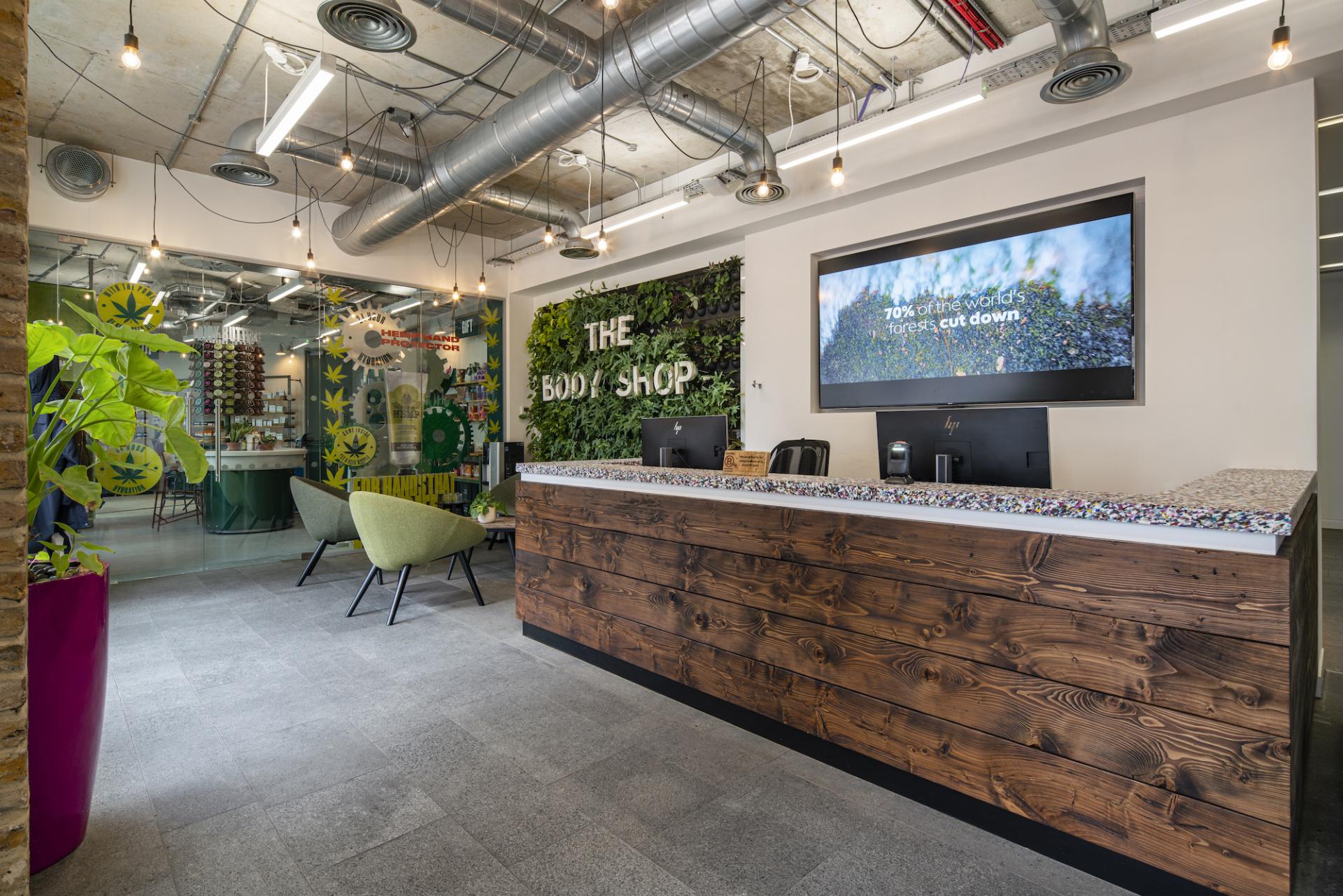 Modern reception area of The Body Shop featuring eco-friendly design elements and a data-driven display about sustainability.