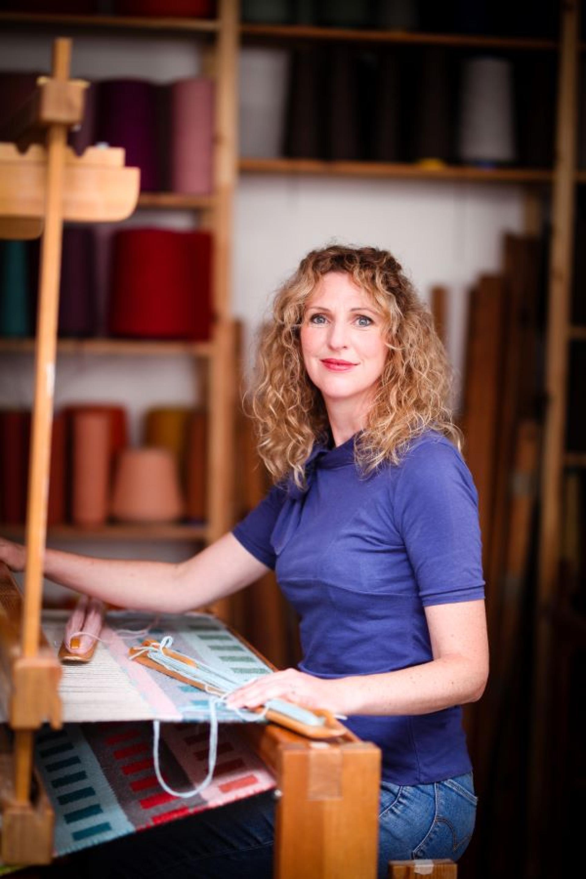 Craftsperson weaving colorful fabric on a loom in a creative Bristol studio, showcasing the art of textile craftsmanship.