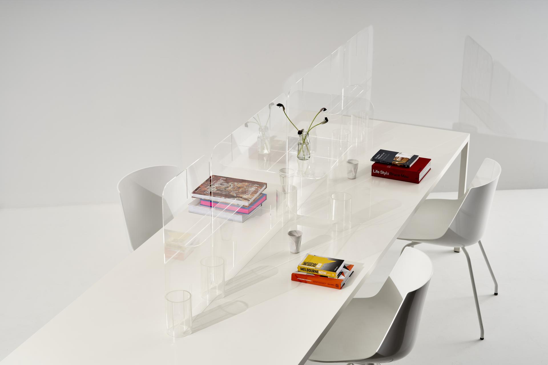 Modern workspace featuring clear acrylic dividers on a sleek table, promoting safe collaboration in design.