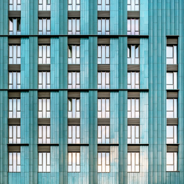 Modern architectural facade featuring turquoise ceramic tiles and a rhythmic pattern of windows, embodying the ceramic renaissance.
