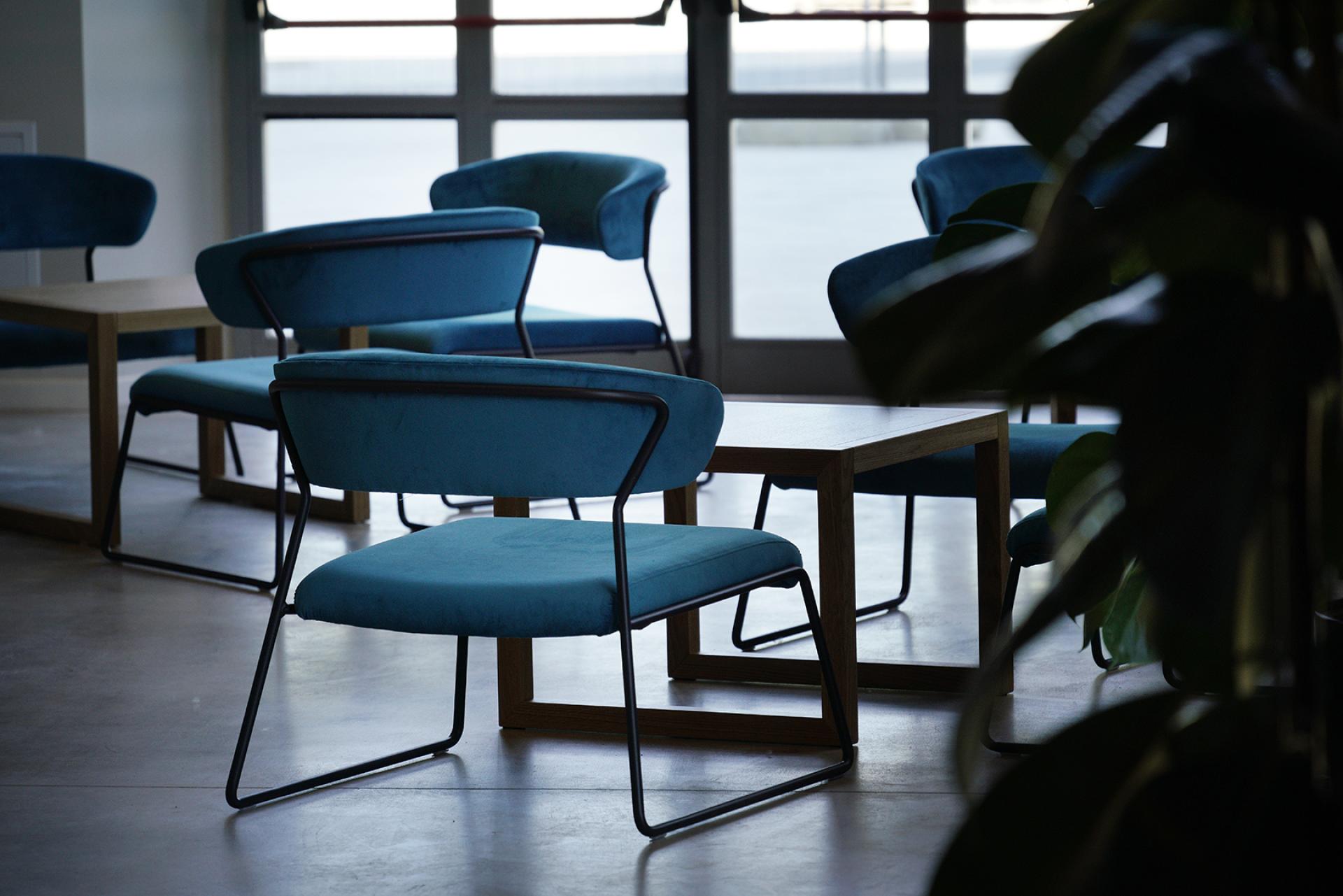 Sleek blue chairs and wooden tables set in a modern socio-cultural hub within the former Daste power plant.