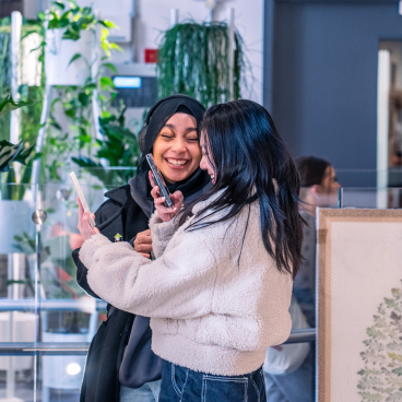 Two women engage in conversation while browsing design materials during MMU's Green Week event.