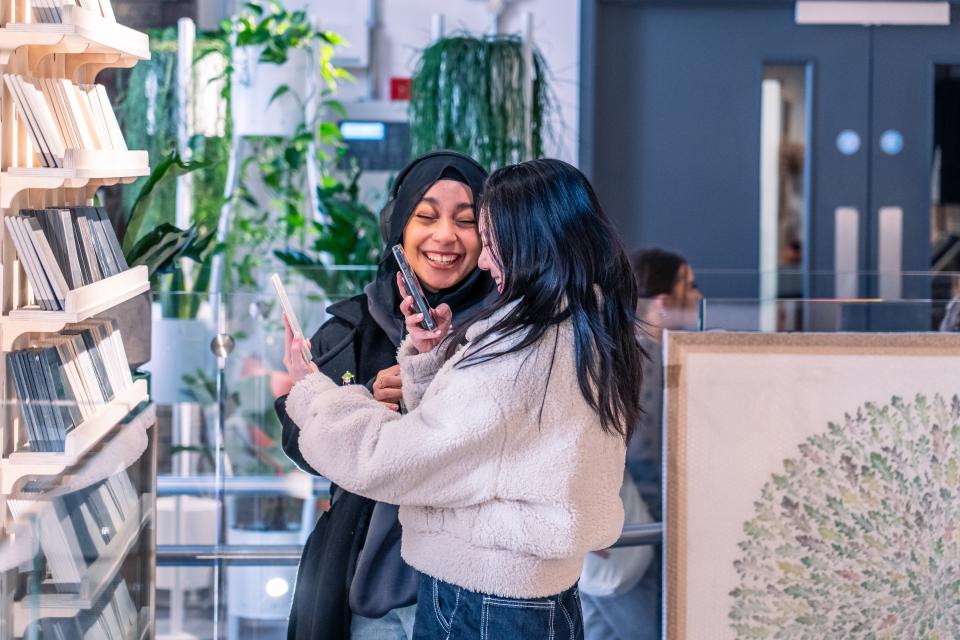 Two women engage in conversation while browsing design materials during MMU's Green Week event.