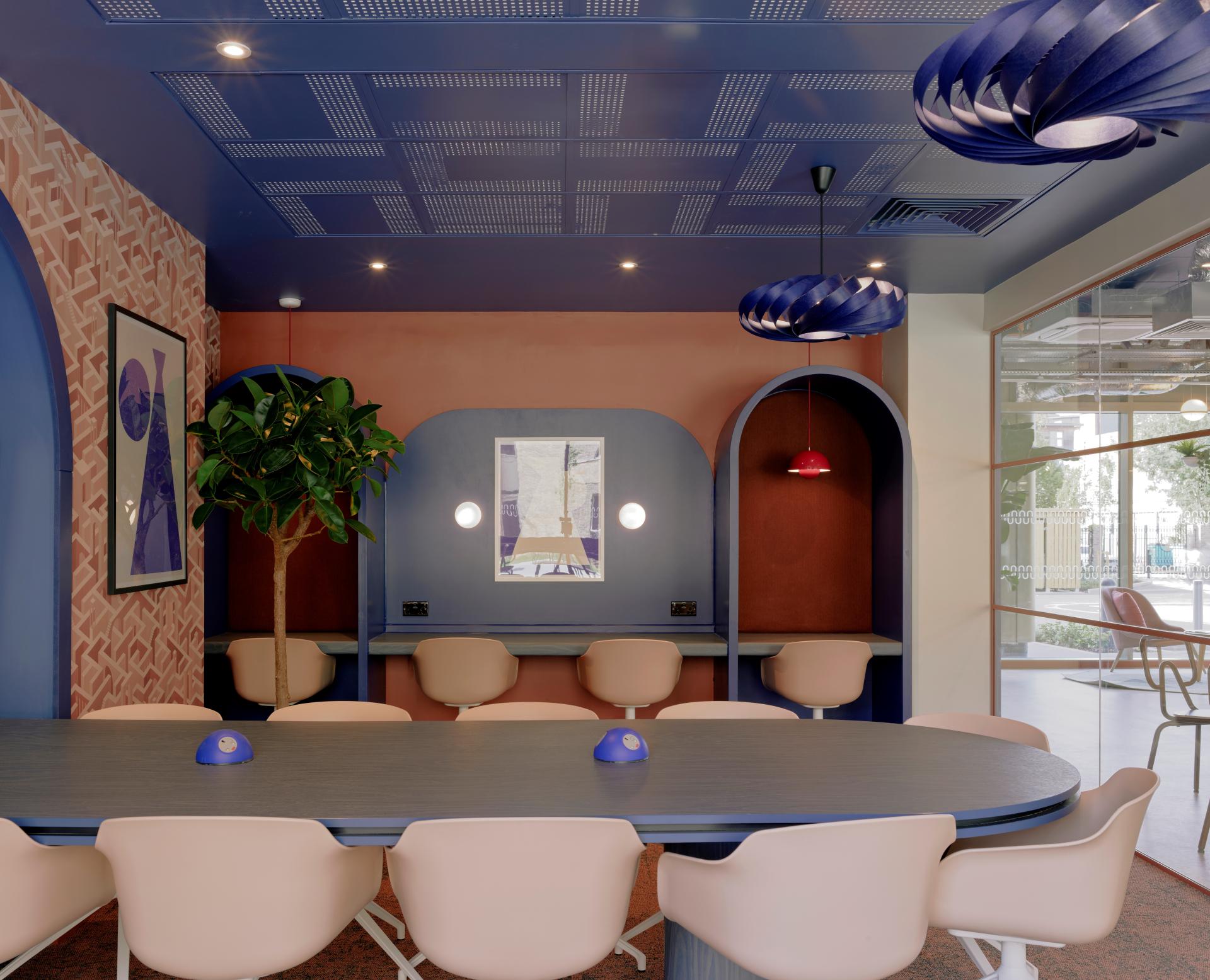 Modern communal workspace at Enso in Colchester, featuring colorful decor, stylish seating, and artistic lighting elements.