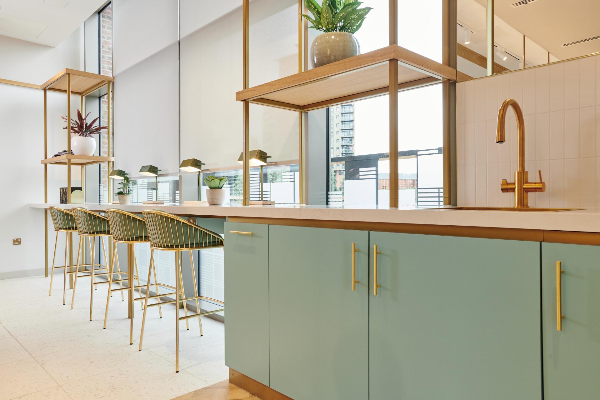 Modern residential kitchen design featuring light teal cabinets, gold fixtures, and stylish bar stools at The Headline, Leeds.