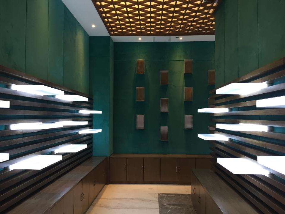 Modern interior design of a sensory experience space in a Chinese liquor factory, featuring green walls and illuminated shelves.