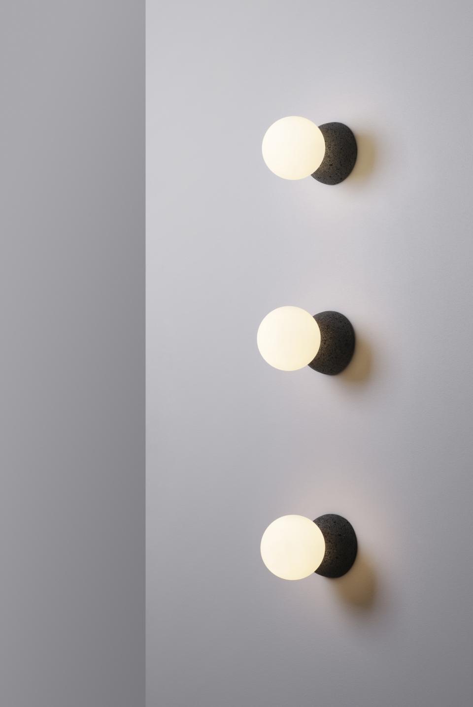 Origo lighting collection featuring spherical lights mounted on textured volcanic rock, creating a modern, artistic display.