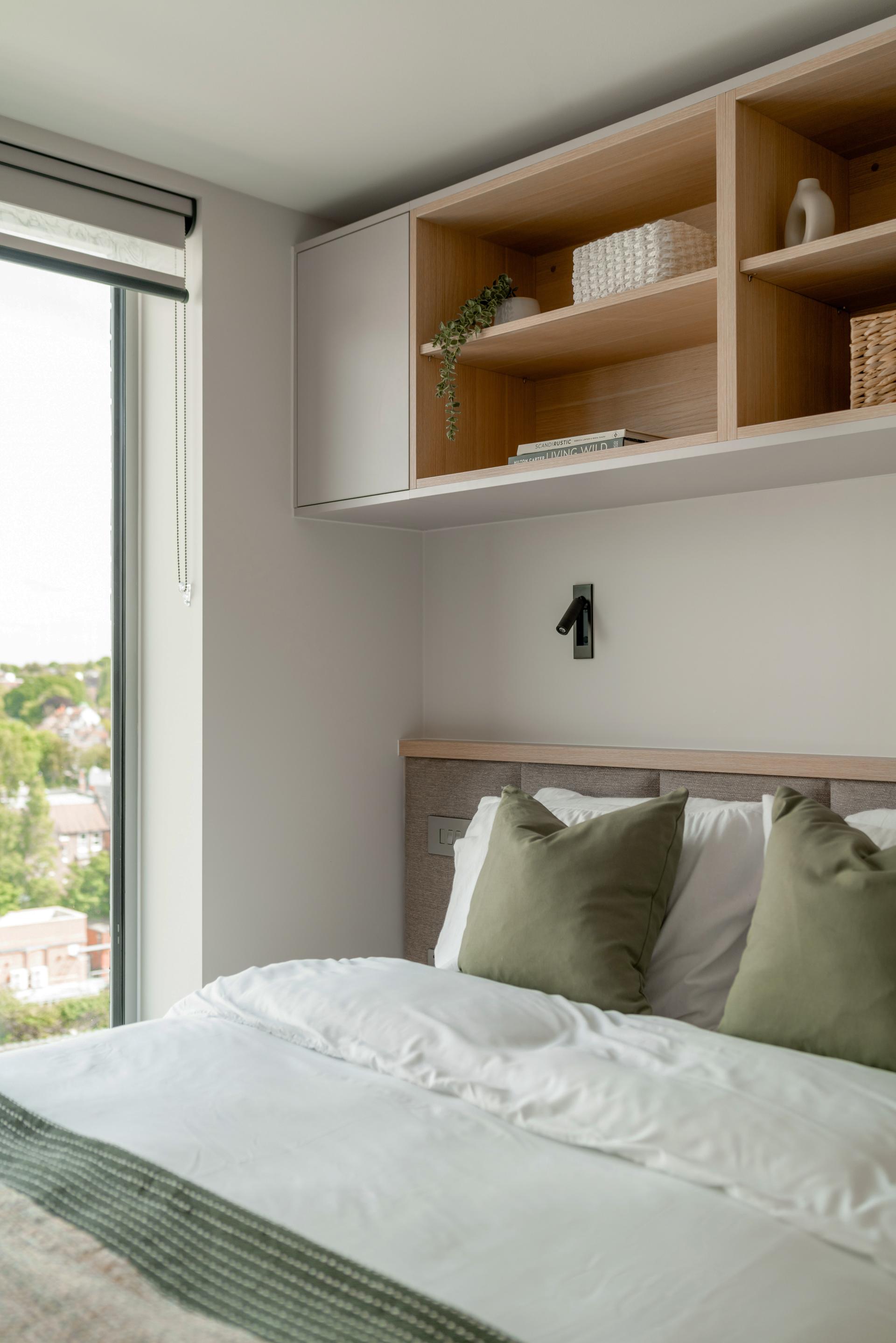 Modern co-living bedroom featuring stylish decor, green accents, and natural light from large windows.