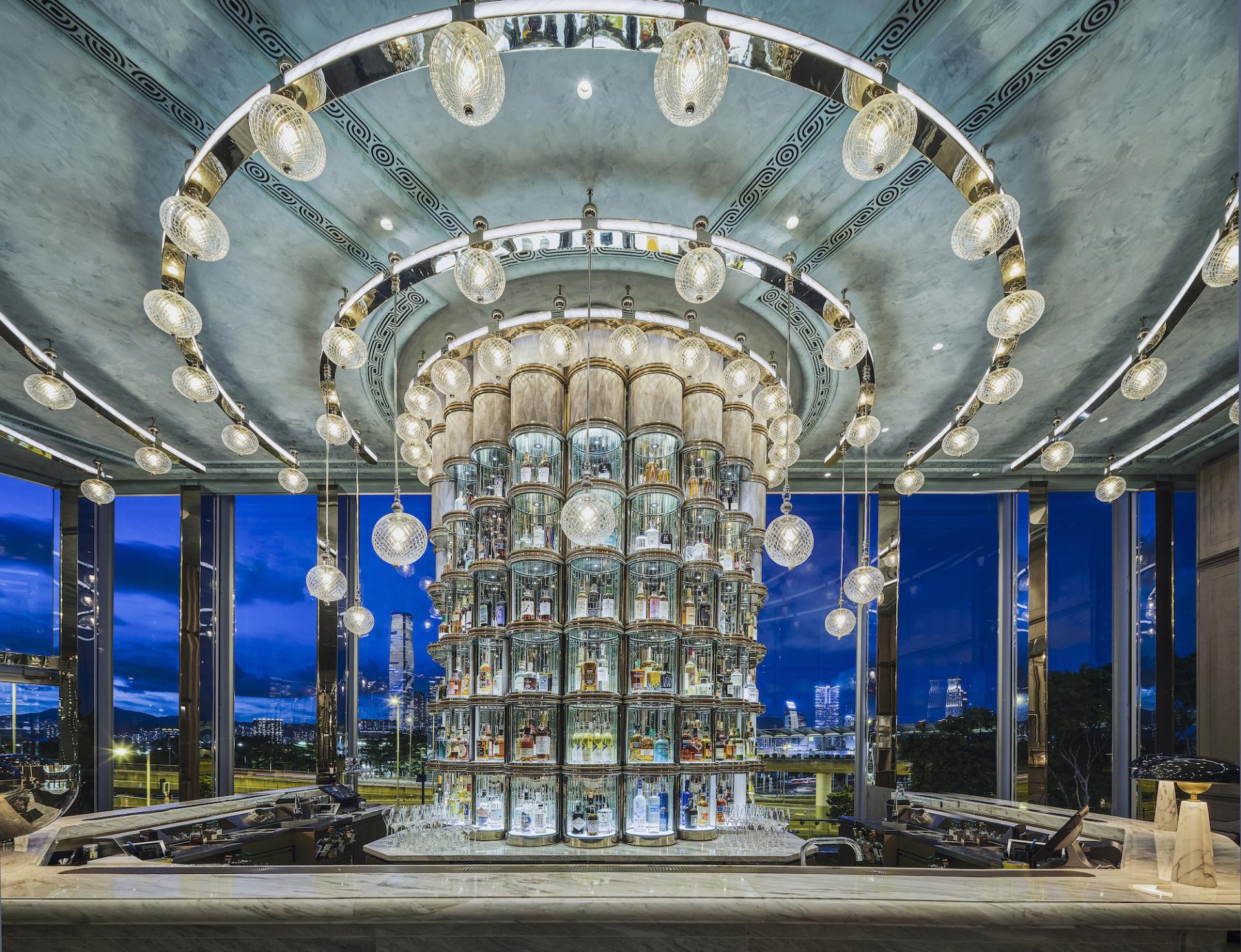 Elegant cocktail bar design at Argo, Four Seasons Hong Kong, featuring a stunning illuminated bottle display and city views.