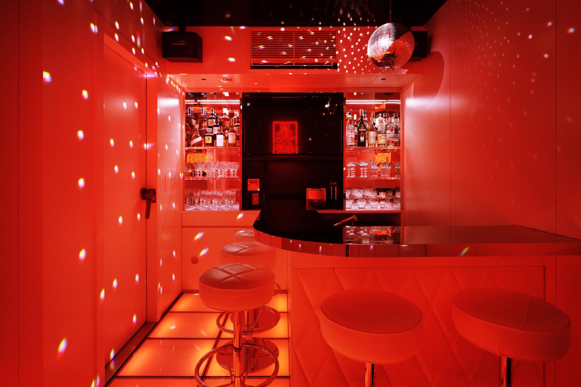 Vibrant interior of TRUNK(HOUSE) bar in Kagurazaka, Tokyo, featuring red lighting and sleek seating.