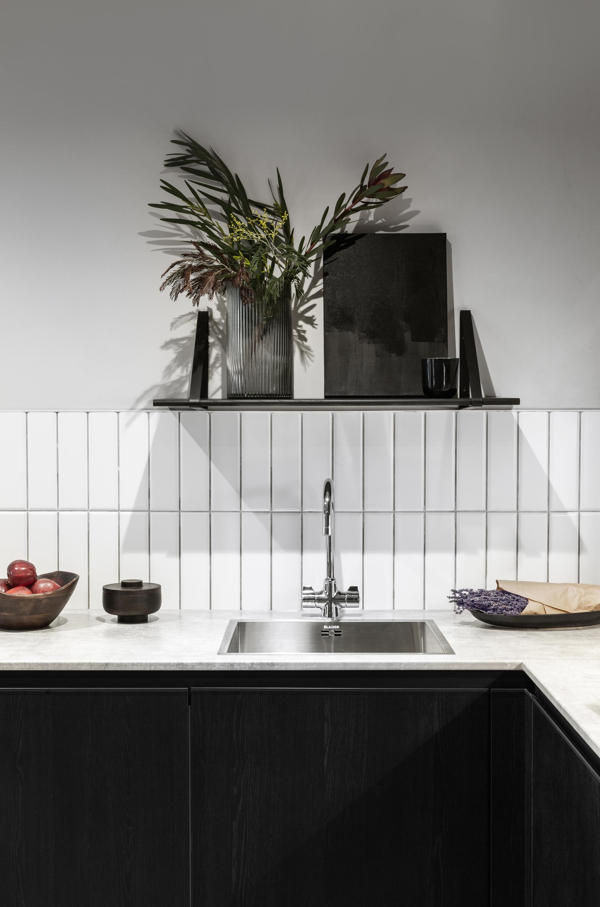 Modern kitchen with dark cabinetry, decorative plants, and stylish accessories, reflecting contemporary design in Manchester.