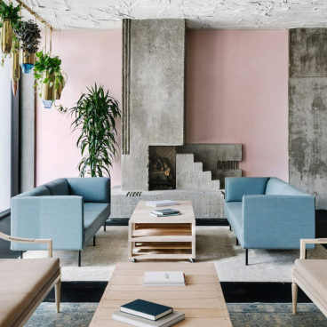 Stylish mid-century hotel lobby in Austin featuring pale pink walls, modern furniture, and lush greenery.