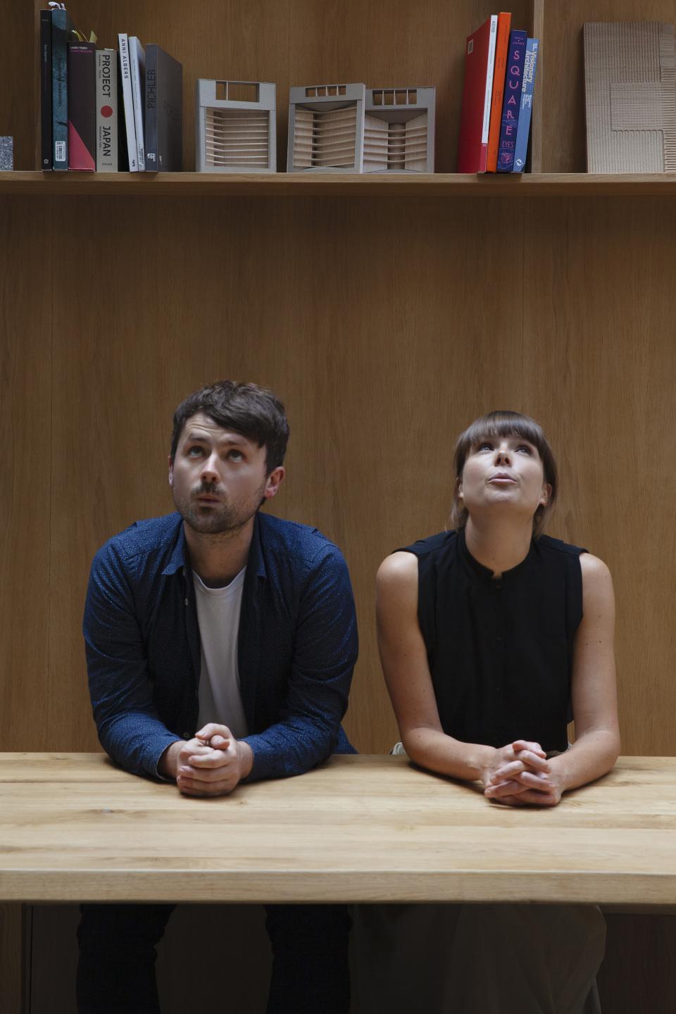 Architects at THISS studio engaged in creative brainstorming, surrounded by design books and architectural models.