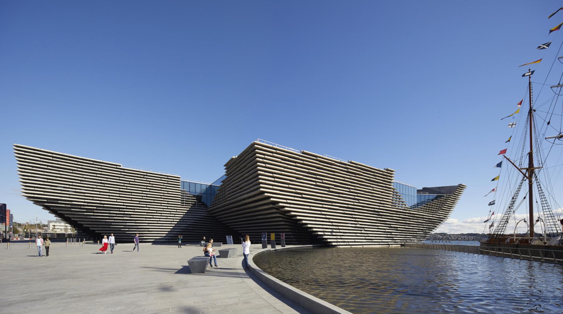 V&A Dundee features striking, light-filled architecture by Kengo Kuma, showcasing distinctive layered exterior design and surrounding water.