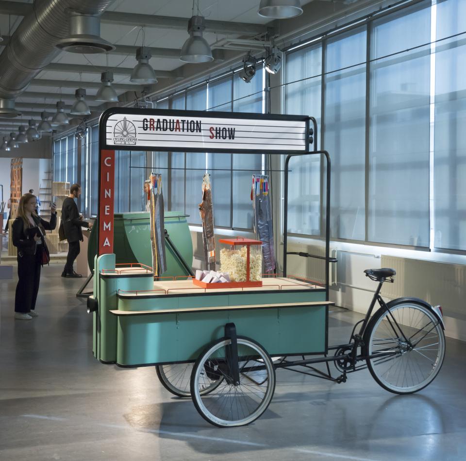 Colorful graduation show display with popcorn cart bike, showcasing innovative designs at Dutch Design Week event.