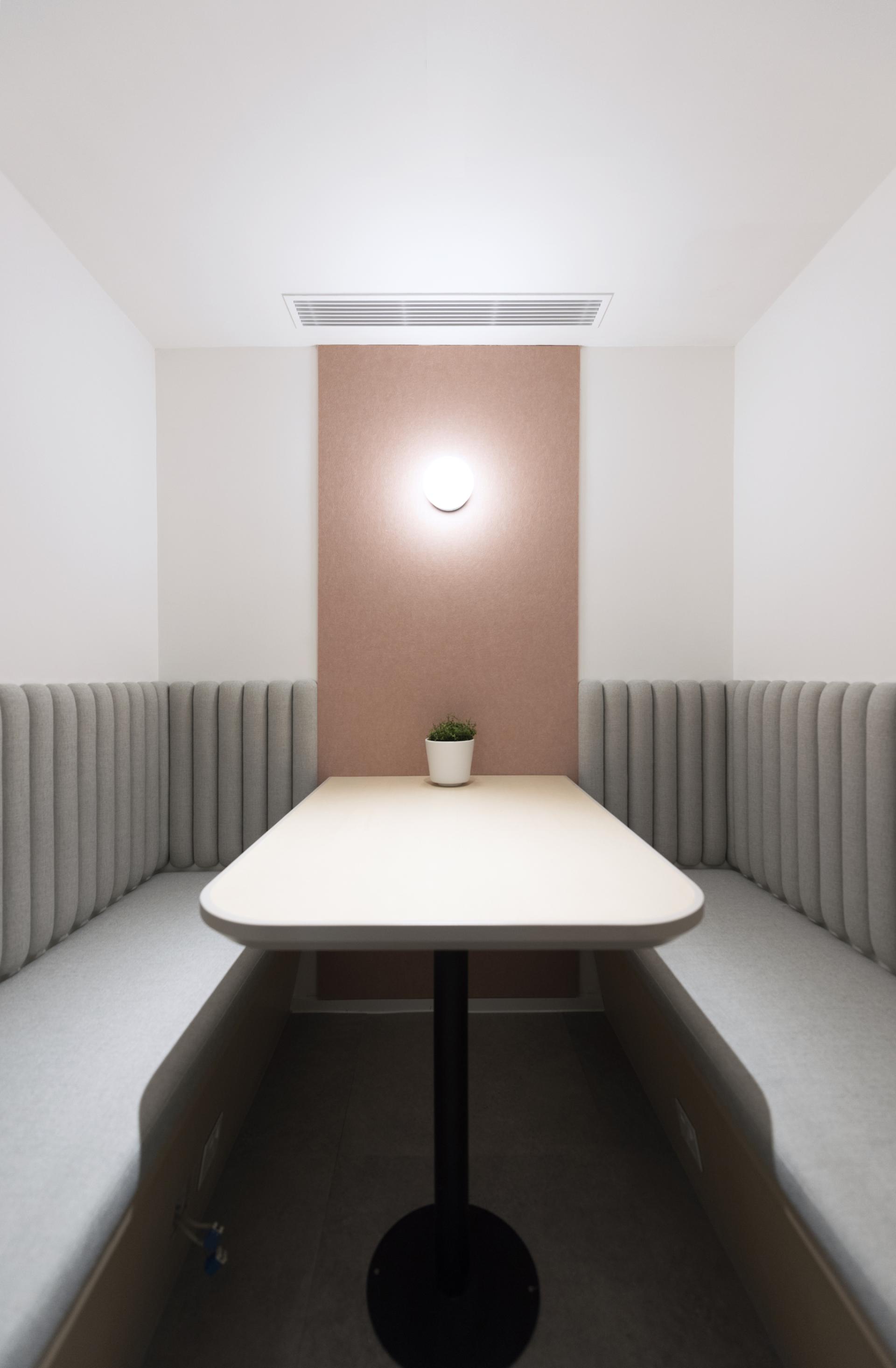 Modern design workspace with plush seating, a minimalist table, and a potted plant, inspired by educational themes.