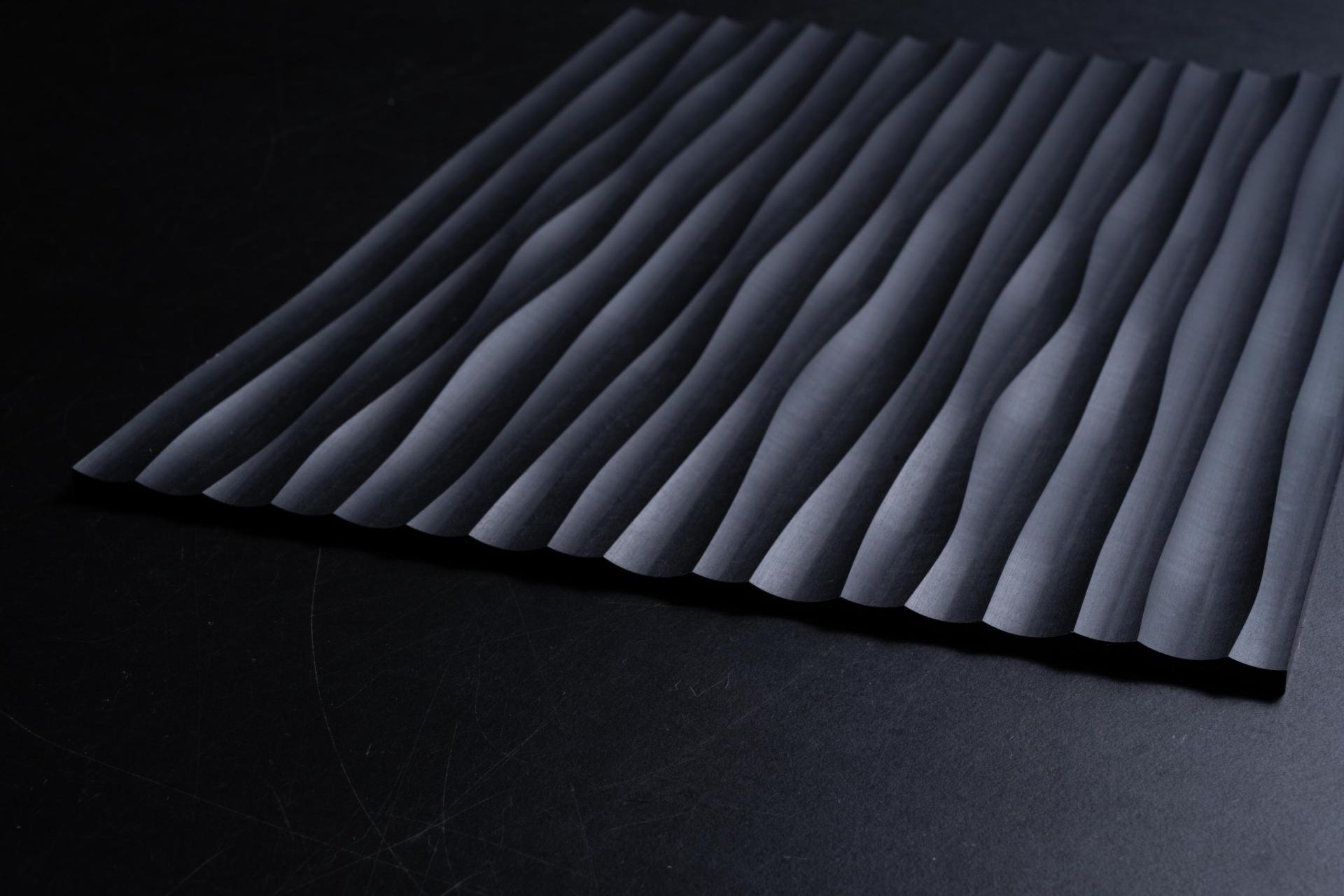 Textured black material with wavy patterns, showcasing Surface Matter's circular Material Rescue initiative for innovative design solutions.