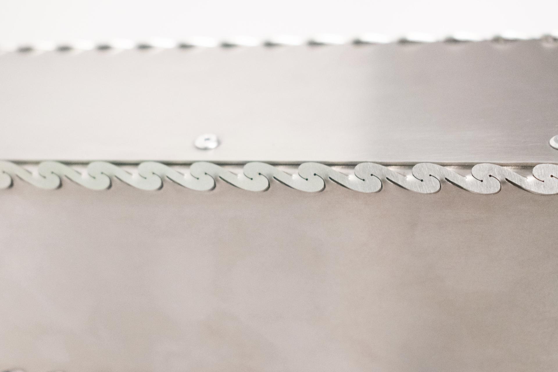 Sleek metallic surface featuring intricate laser-etched wave patterns, highlighting innovative craftsmanship at Dutch Design Week 2024.