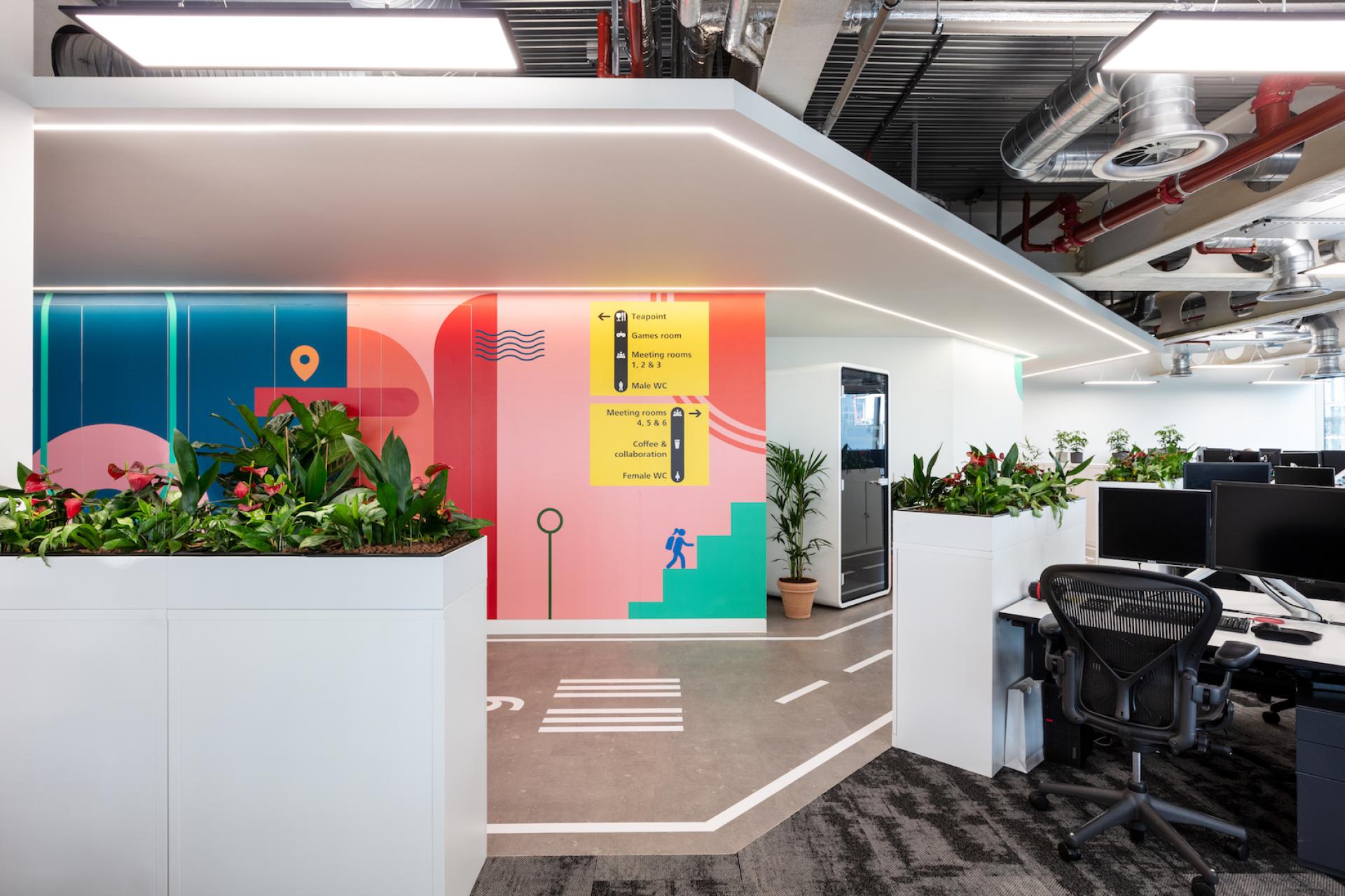 Brightly designed office interior featuring signage, plants, and modern workspaces, showcasing Modus's fit-out for Travelfusion.