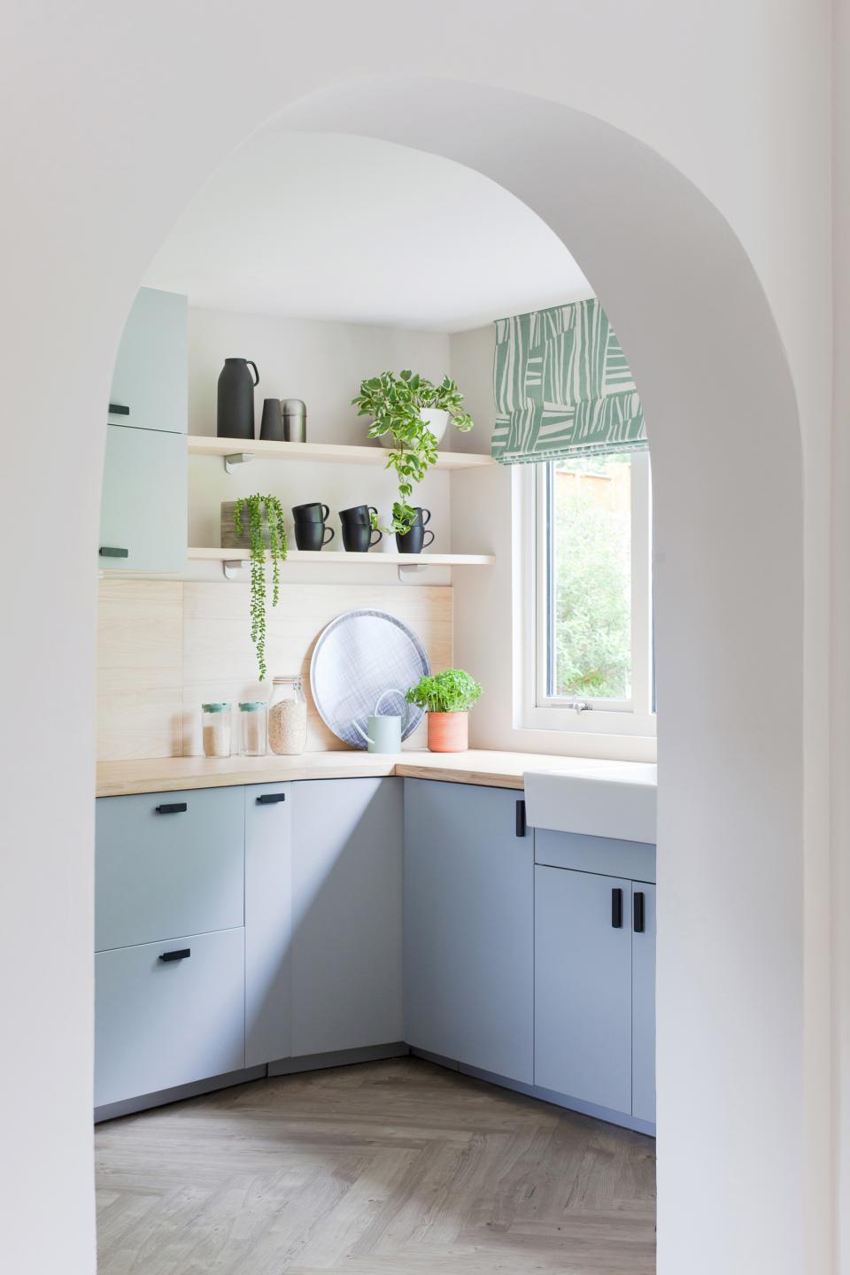 Modern Scandi Industrial-style kitchen featuring blue cabinetry, wooden countertops, and vibrant greenery for a fresh look.
