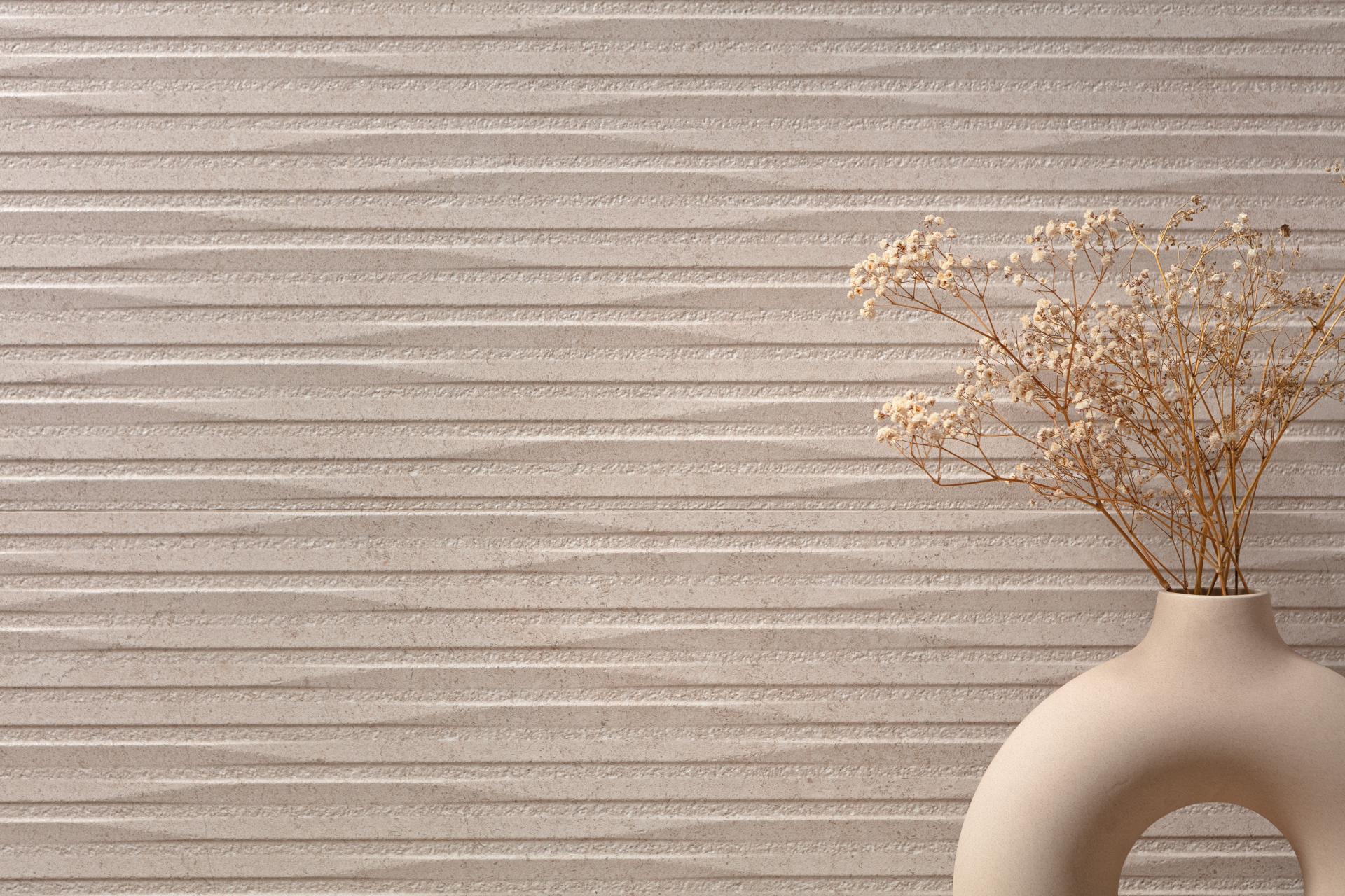 Textured beige ceramic wall with a minimalist vase featuring dried flowers, illustrating contemporary tile trends from Cevisama 2023.