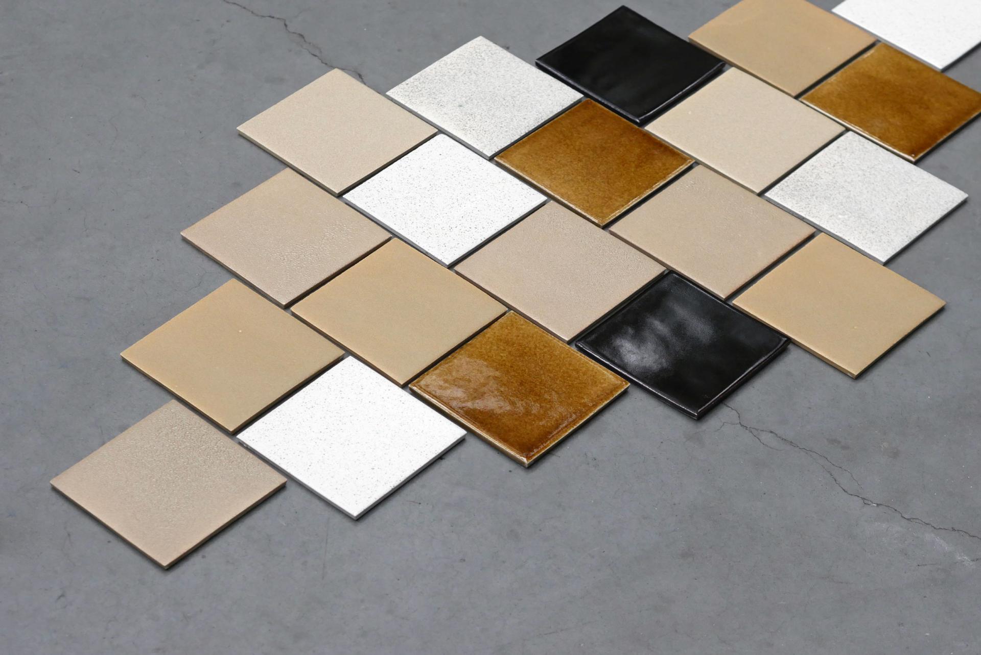 Colorful ceramic tiles arranged artistically on a gray surface, embodying Agnė Kučerenkaitė's innovative design philosophy.