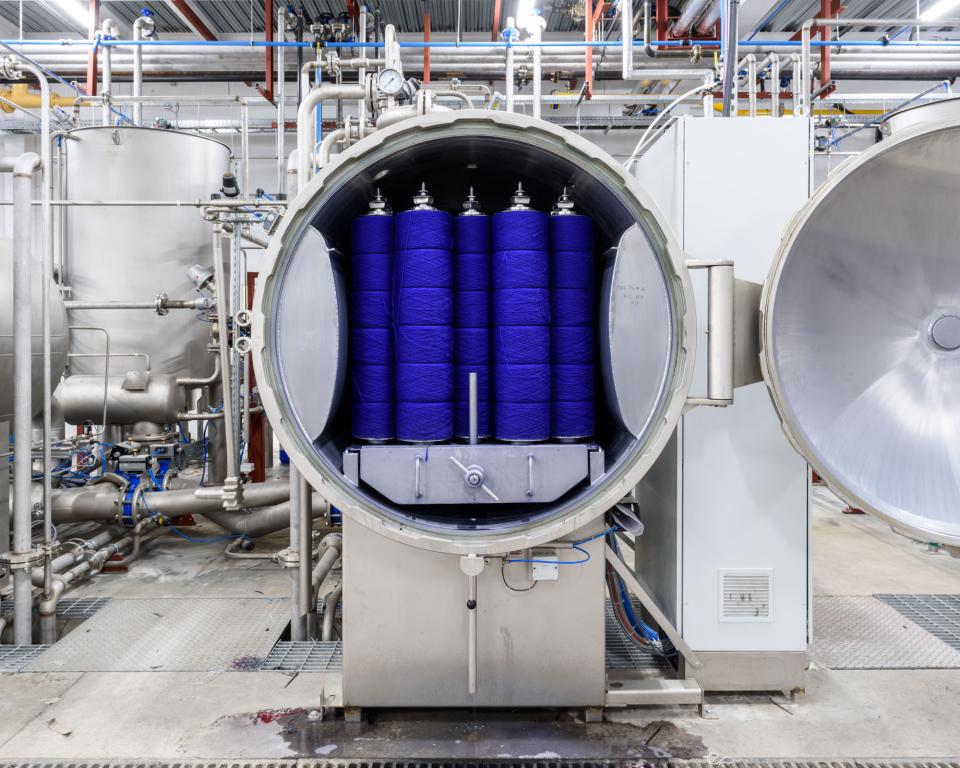 Industrial machine featuring spools of vibrant blue upholstery yarn, part of Kvadrat's textile manufacturing process.